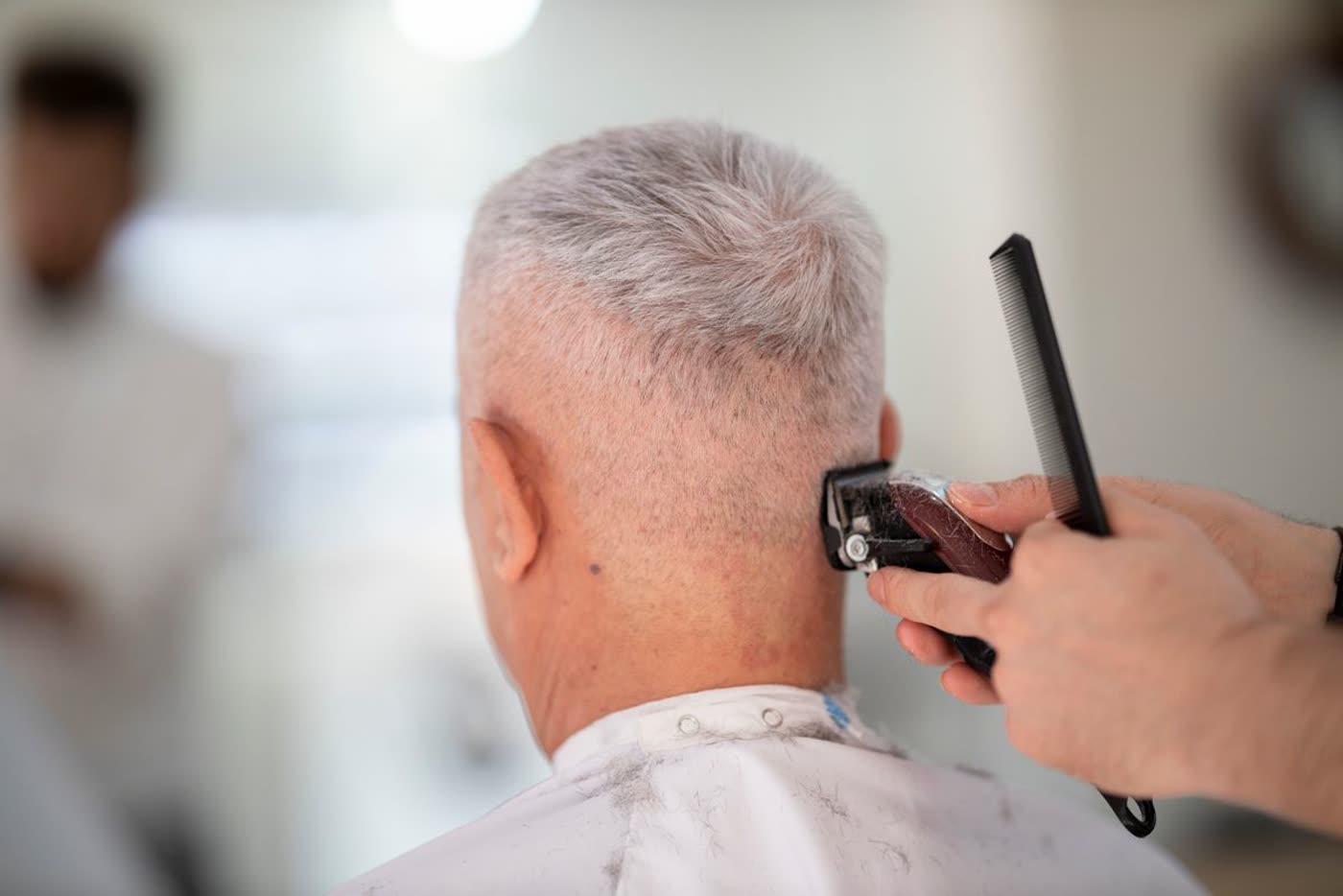 A crisp silver men's cut mid-fade at the chair
